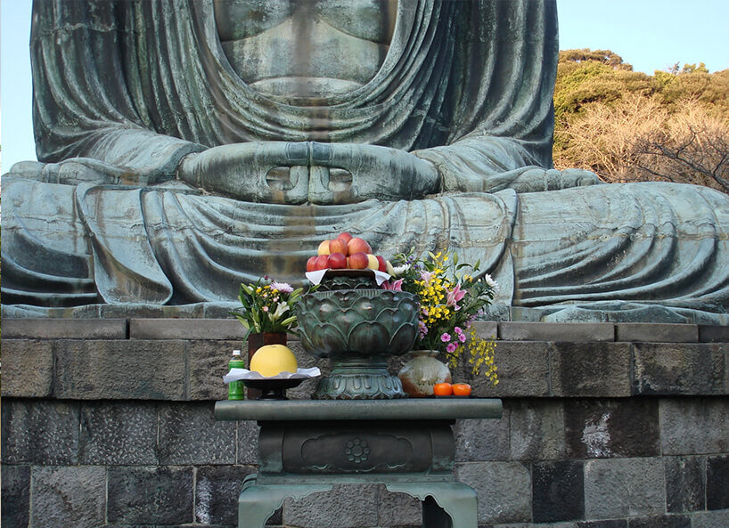 abgelegter Blumenschmuck vor Buddha