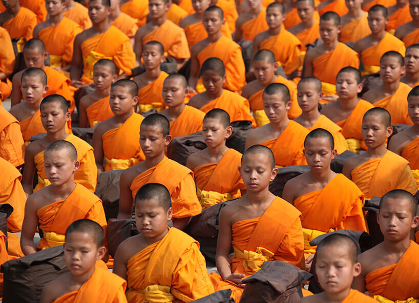 Junge Japaner beim Meditieren mit orangener Kleidung
